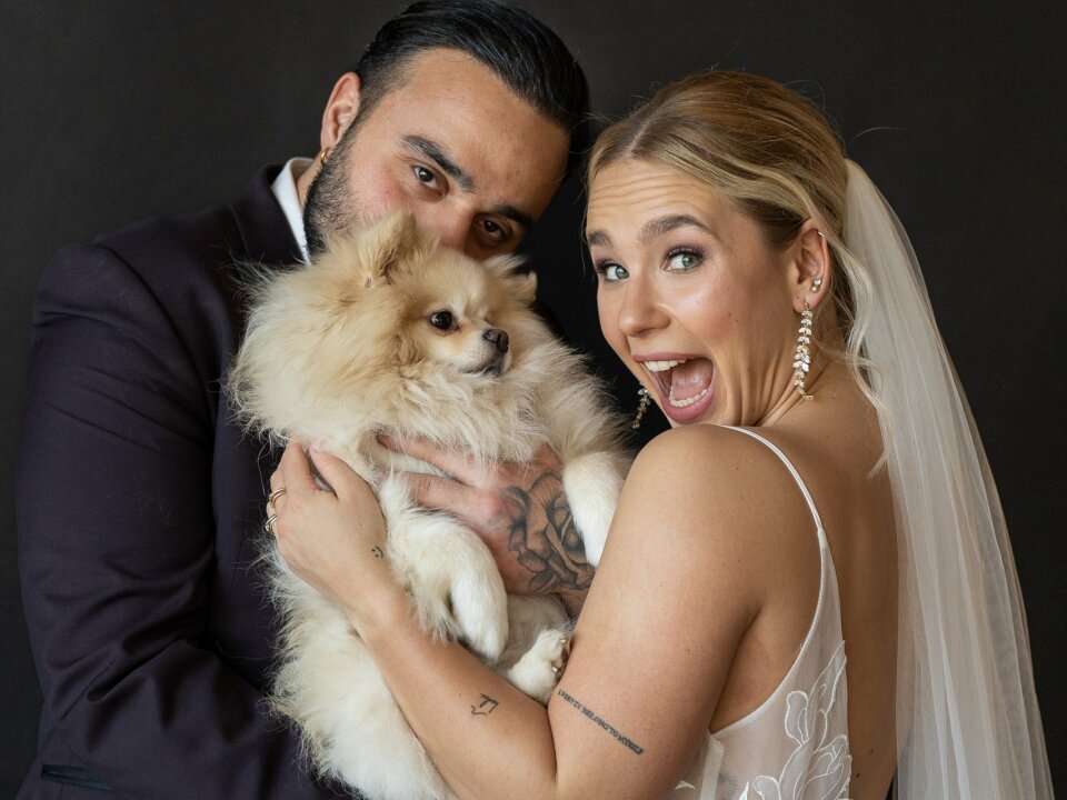 een bruid en bruidegom die poseren voor een foto met een hond