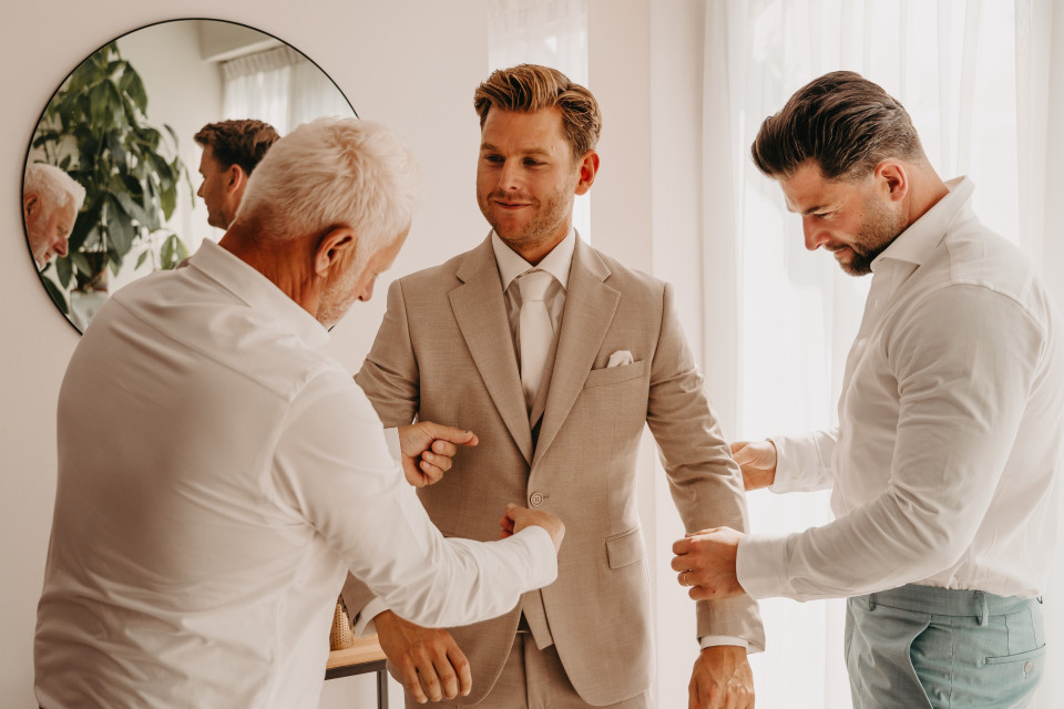 drie mannen in pak helpen elkaar met hun pakken