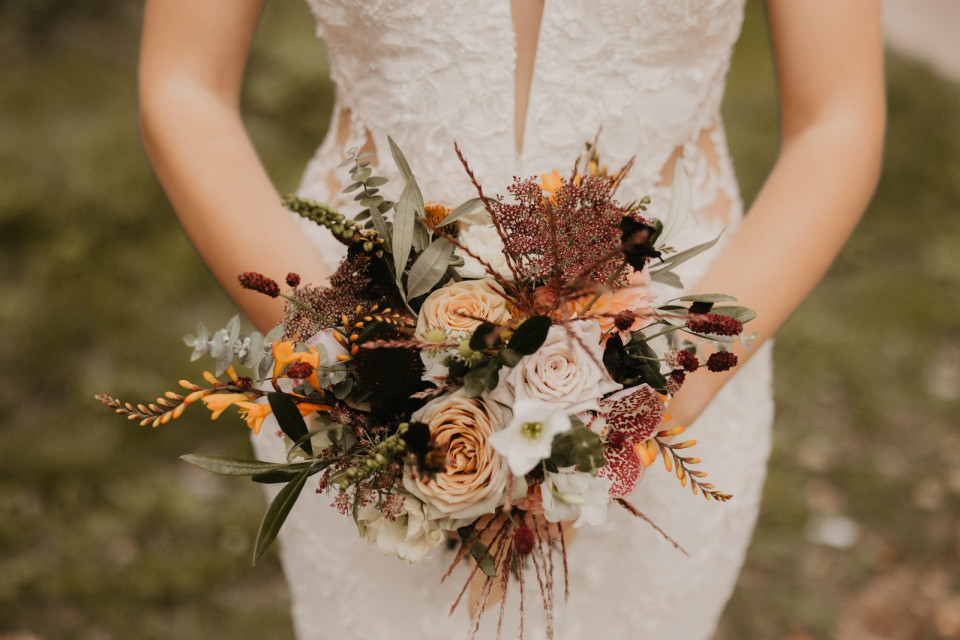 een vrouw in een trouwjurk met een boeket bloemen