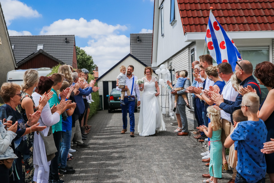 een bruidspaar loopt door de straat terwijl mensen klappen