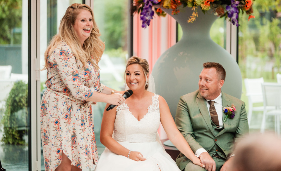 een bruid en bruidegom lachen terwijl de bruidegom een microfoon vasthoudt