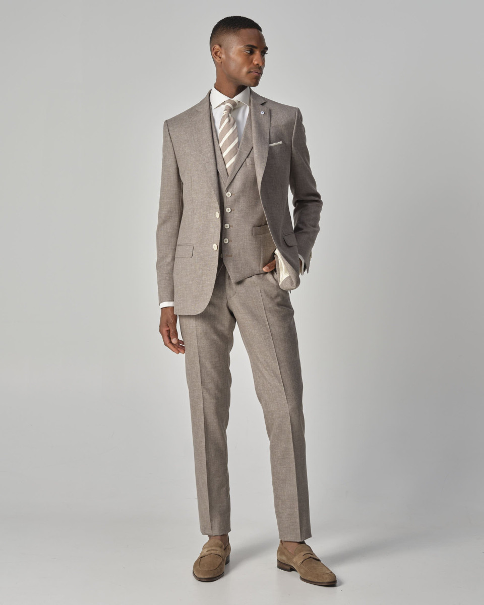 een man in een beige pak en een wit shirt