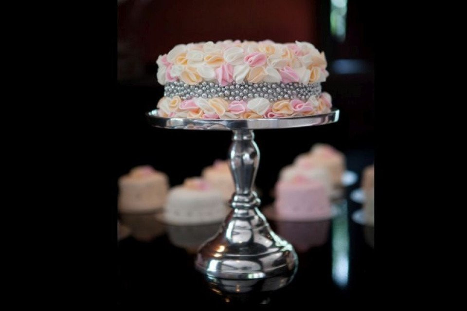 een taart op een zilveren standaard met roze en witte glazuur