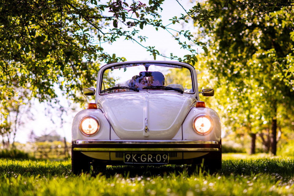 een witte vw-kever geparkeerd in het gras