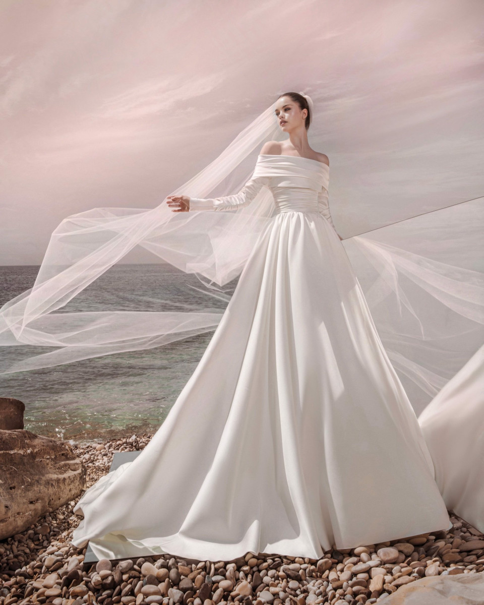 een vrouw in een trouwjurk staat op een rotsachtig strand