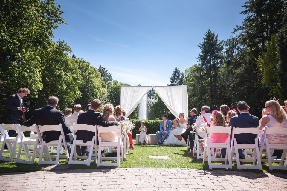een trouwceremonie in de tuin met stoelen en witte gordijnen