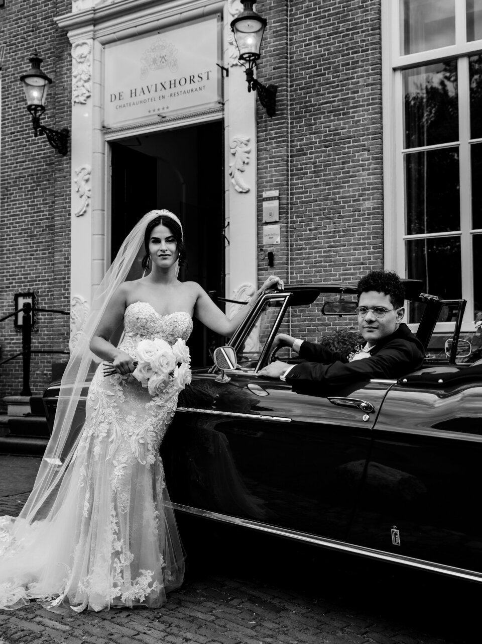 een bruid en bruidegom die achterin een auto zitten