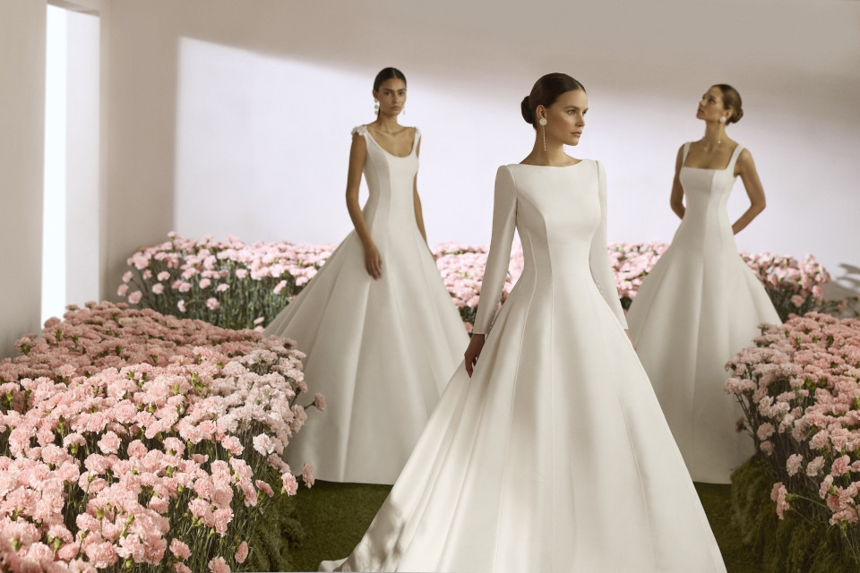 drie vrouwen in witte jurken die in een veld van roze bloemen staan
