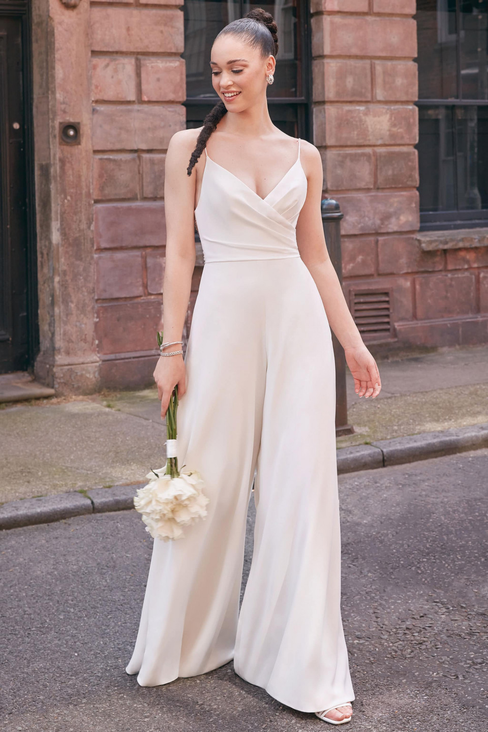 een bruid in een wit jumpsuit en witte bloemen