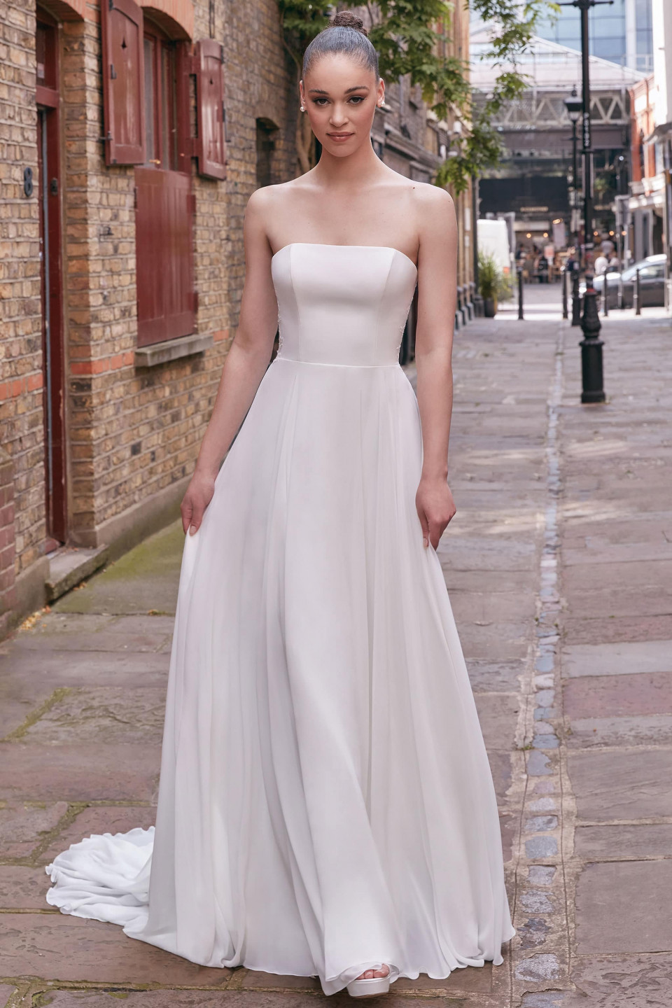 een vrouw in een strapless trouwjurk staat op straat