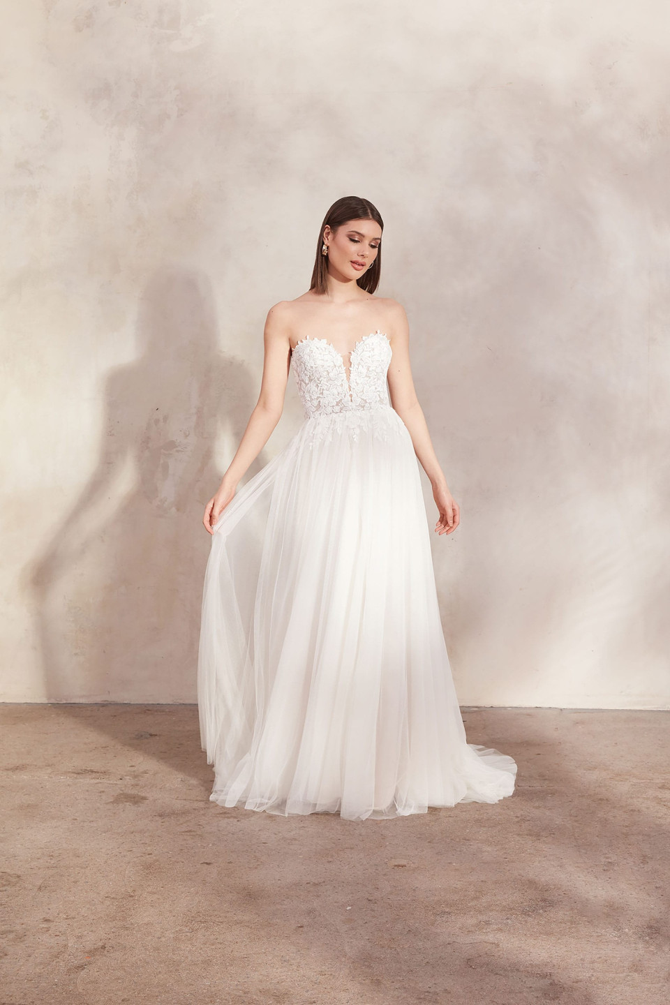 de trouwjurk is een strapless, doorschijnende tule japon met een sweetheart halslijn