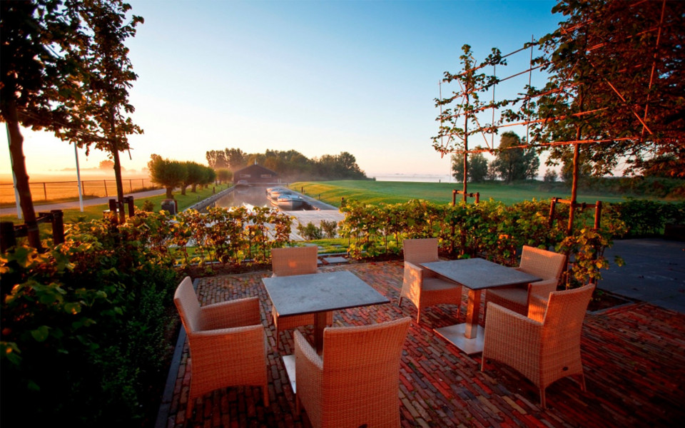 een terras met stoelen en tafels met uitzicht op de golfbaan