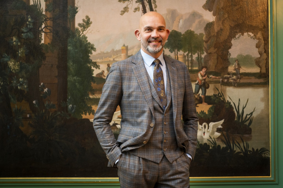 een man in pak en das die voor een schilderij staat