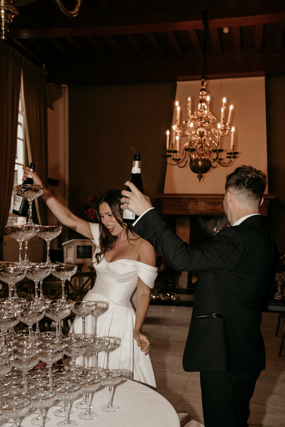 een bruid en bruidegom die champagne inschenken in een toren van wijnglazen