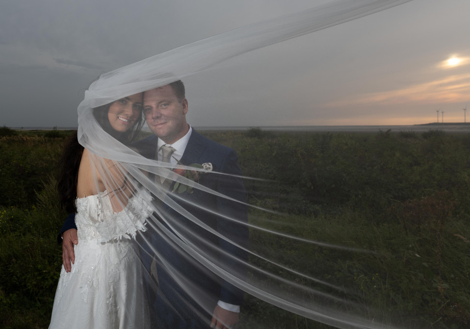 een bruid en bruidegom poseren voor een foto onder een sluier