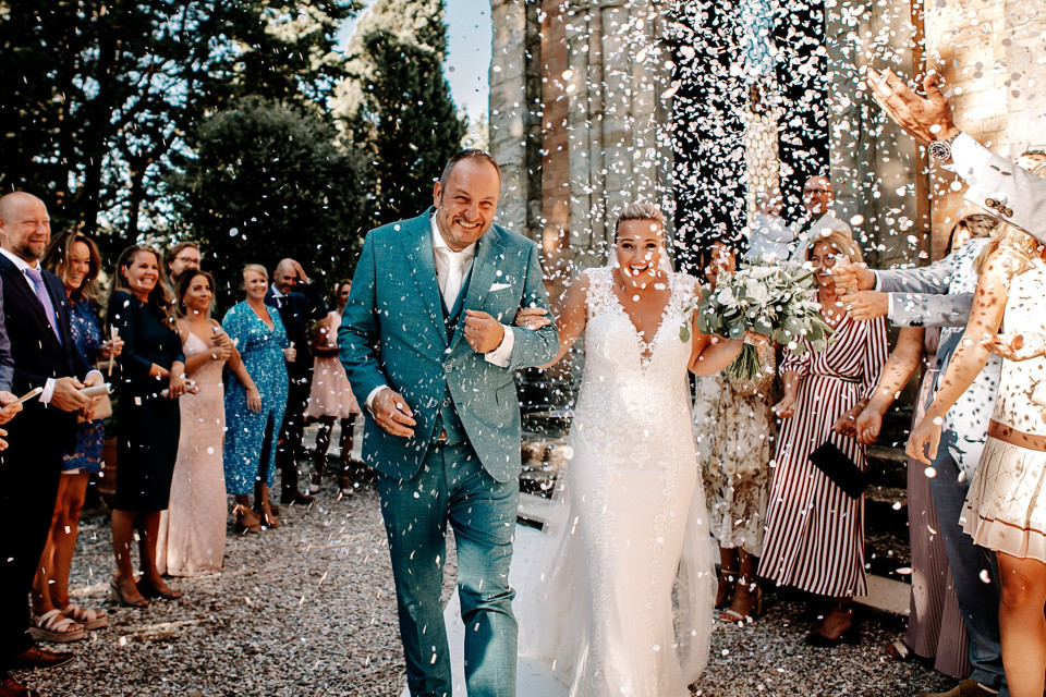 een bruid en bruidegom lopen het gangpad af met confetti