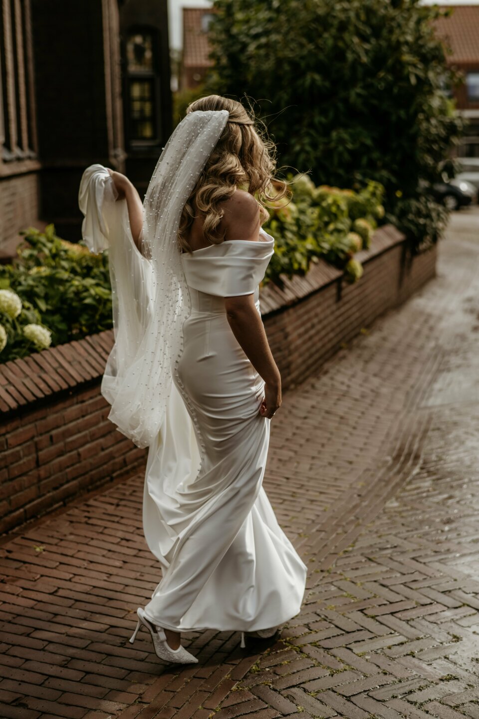 een vrouw in een trouwjurk die door de straat loopt