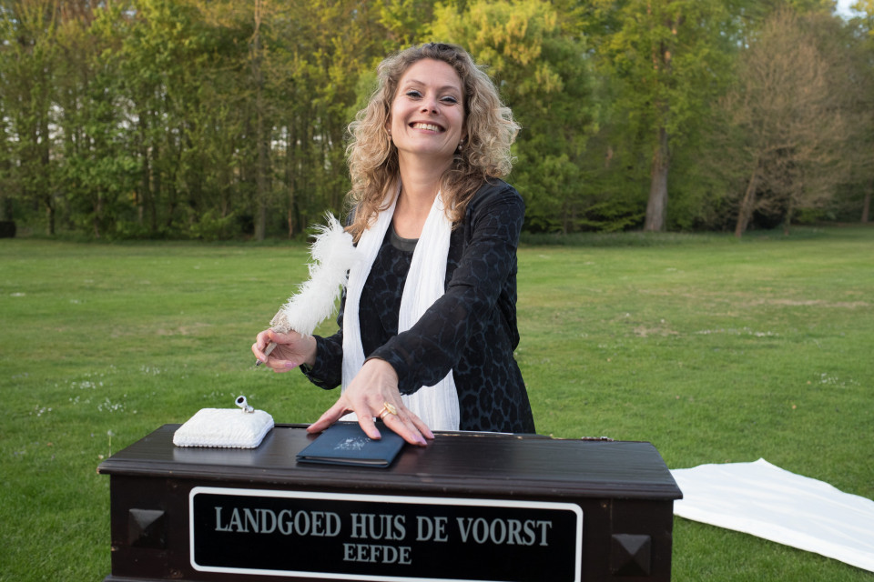 een vrouw staat naast een houten doos met een veer