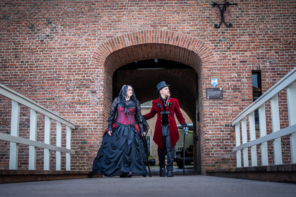twee mensen gekleed in gotische kleding lopen over een brug