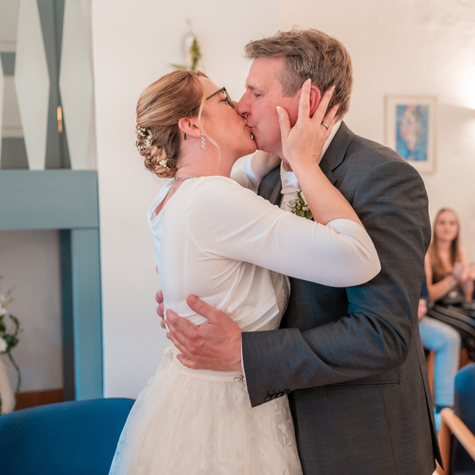 een bruid en bruidegom kussen voor een blauwe stoel