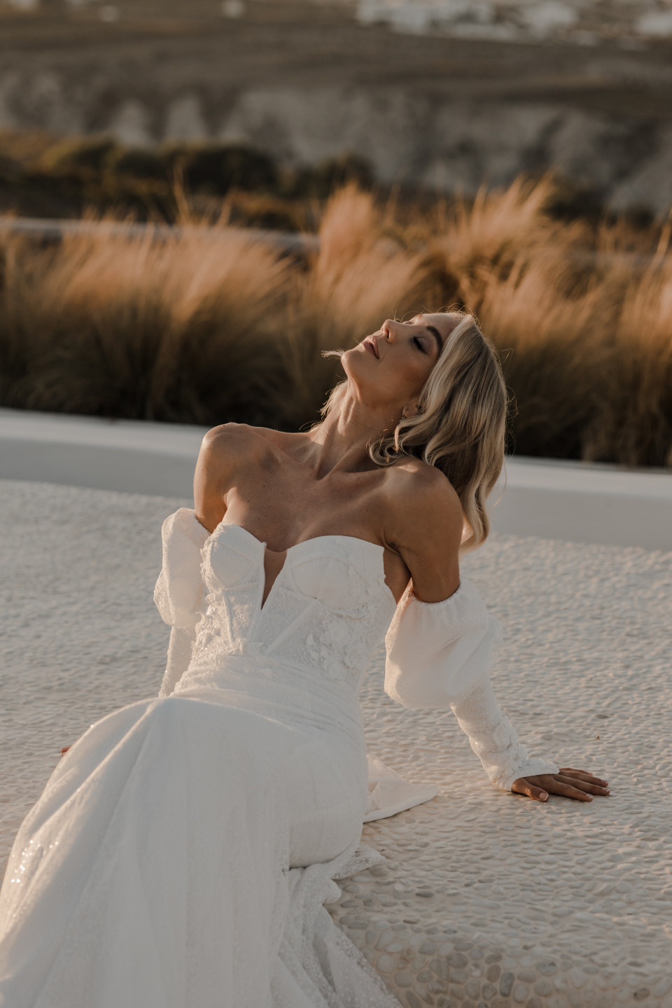 een vrouw in een trouwjurk zittend op een rand