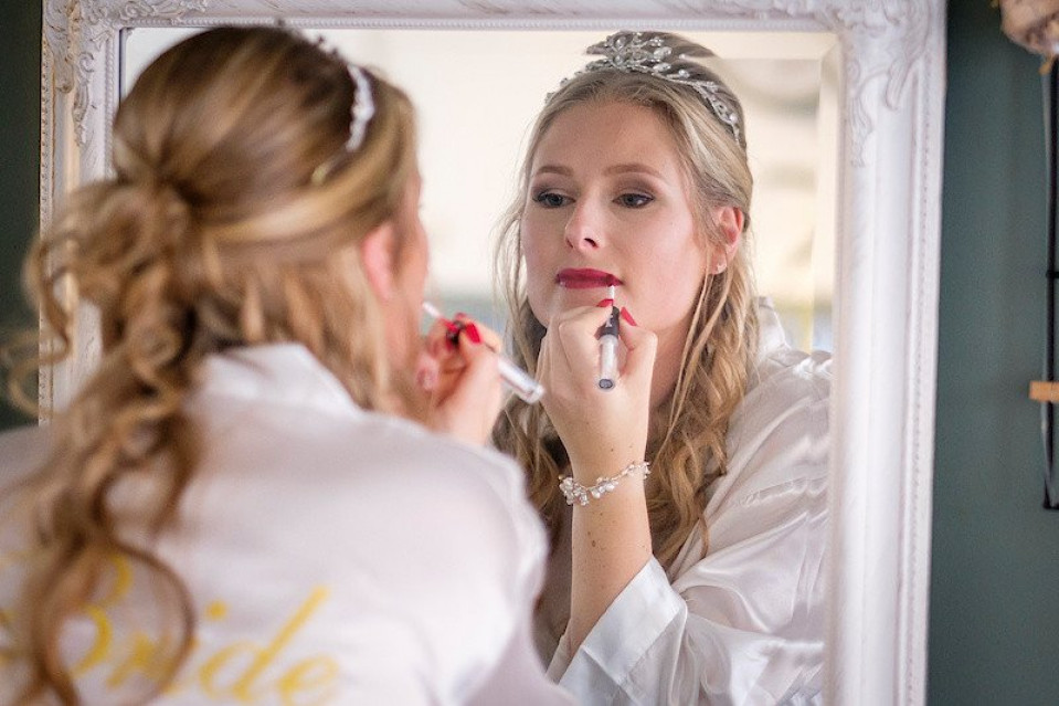 een vrouw in een trouwjurk die haar make-up opdoet
