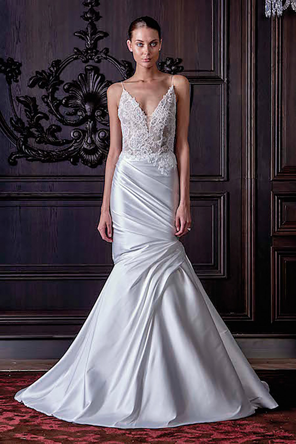 een vrouw in een trouwjurk staat voor een muur