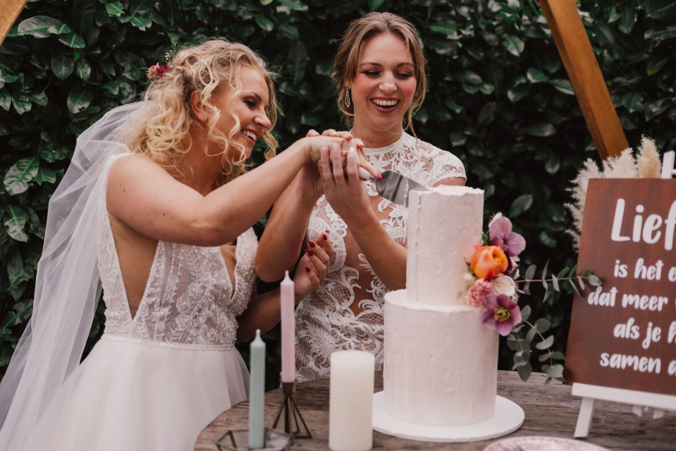 twee bruiden snijden samen een bruidstaart