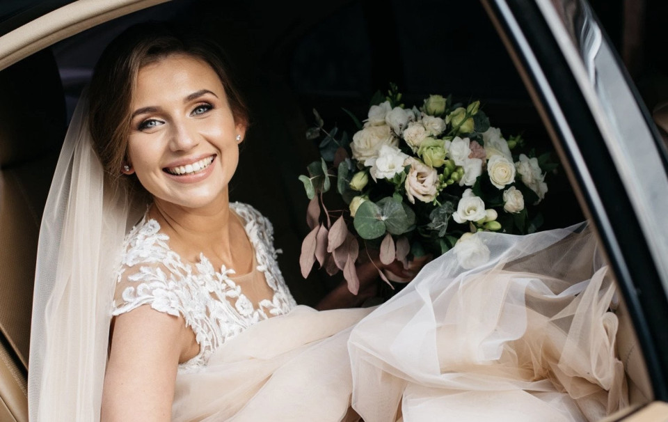 een bruid zittend in haar auto met haar boeket