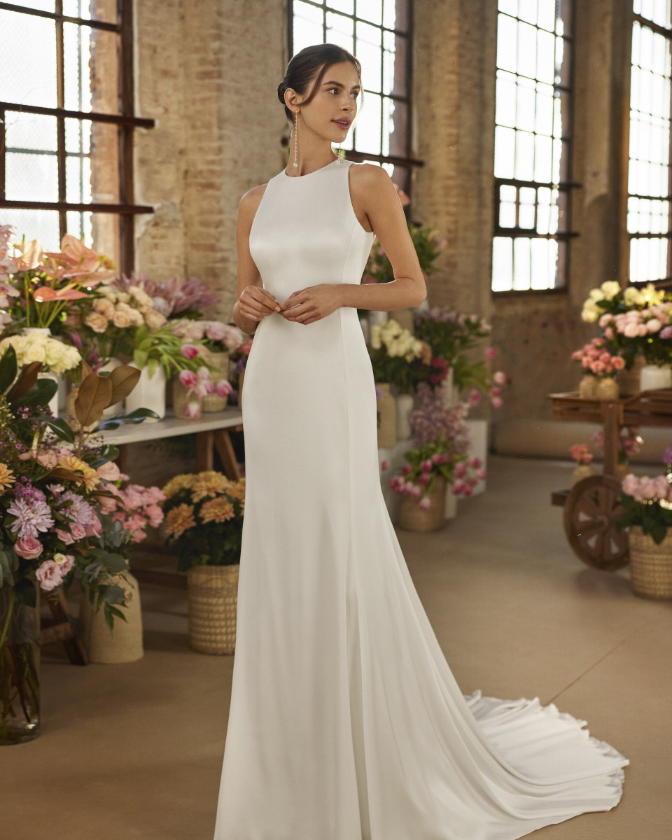 een vrouw in een witte trouwjurk die in een kamer vol bloemen staat