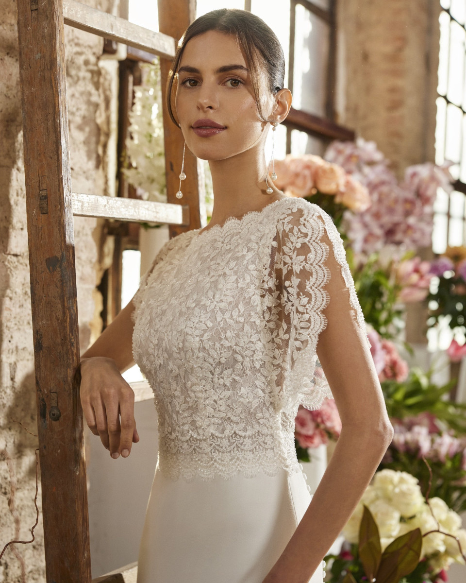 een vrouw in een trouwjurk die voor een bloemenwand staat