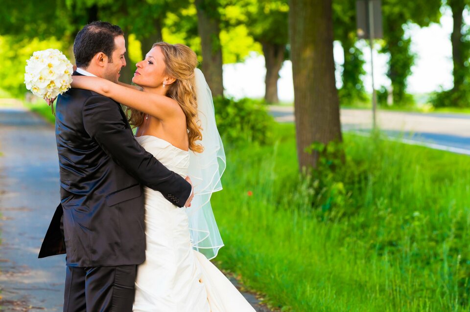 een bruid en bruidegom die in het midden van de weg kussen
