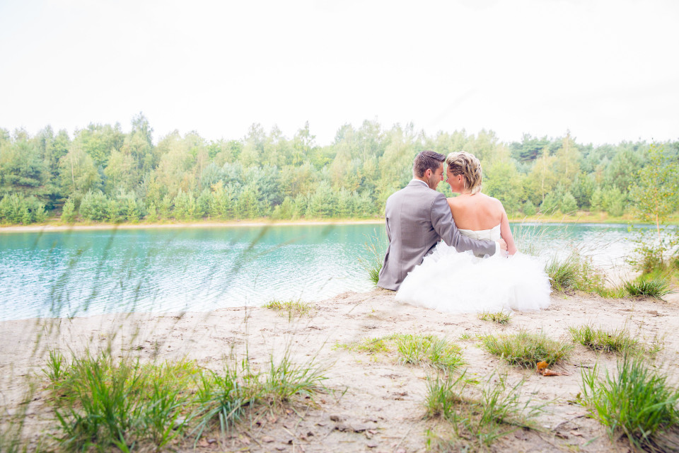 een bruid en bruidegom zitten aan de oever van een meer