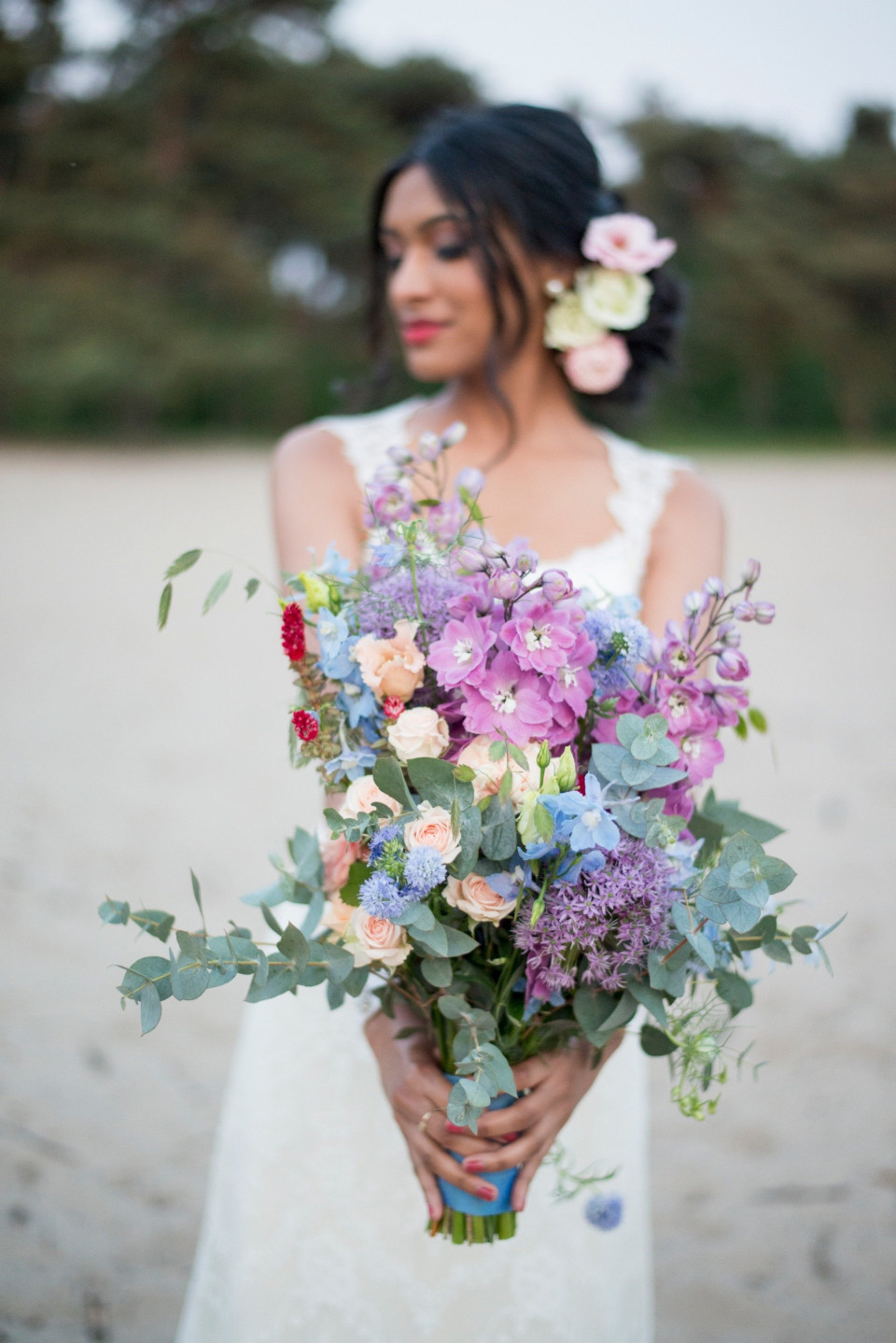 een bruid die een boeket bloemen vasthoudt op het strand