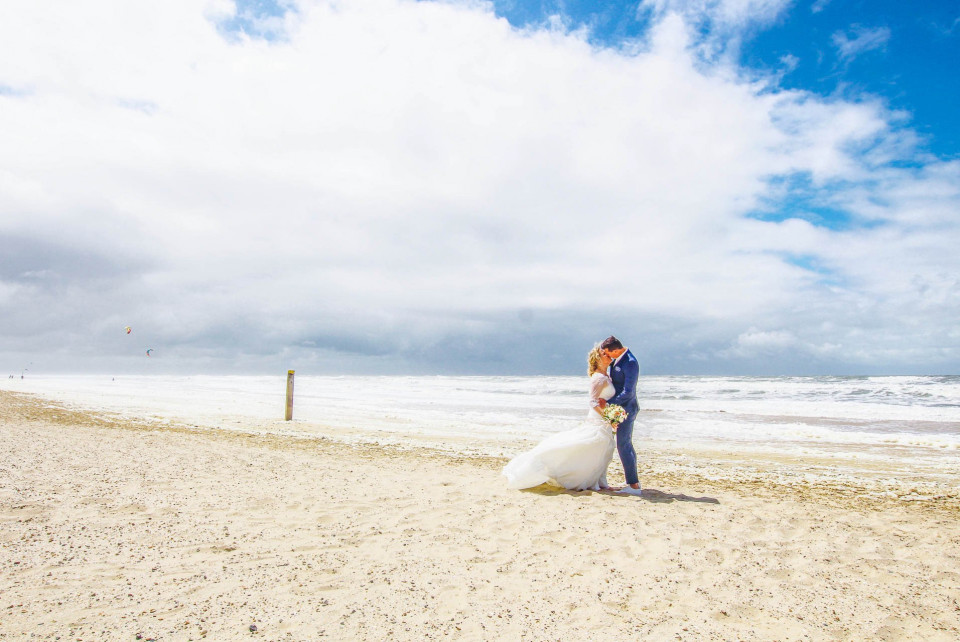 een bruid en bruidegom die op het strand staan