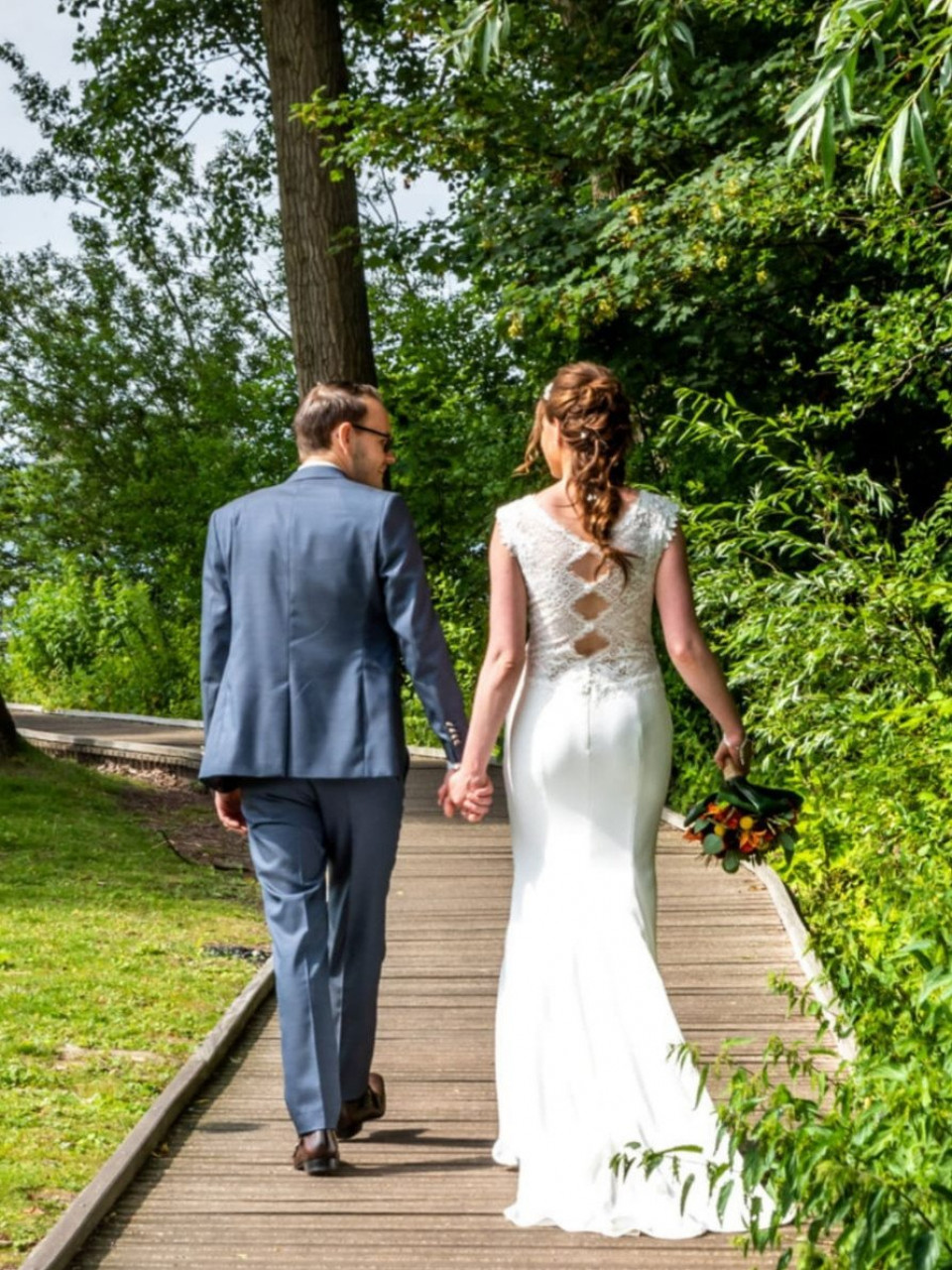 een bruid en bruidegom lopen een pad af in het bos