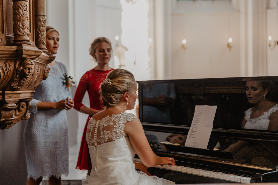 een bruid en bruidegom spelen samen piano
