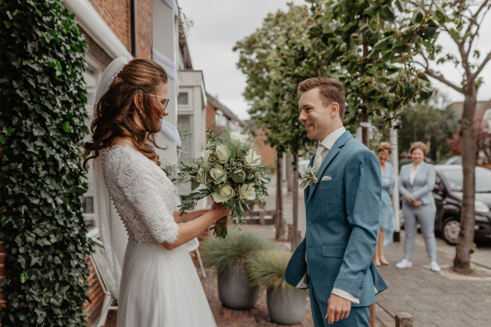 een bruid en bruidegom staan voor een huis