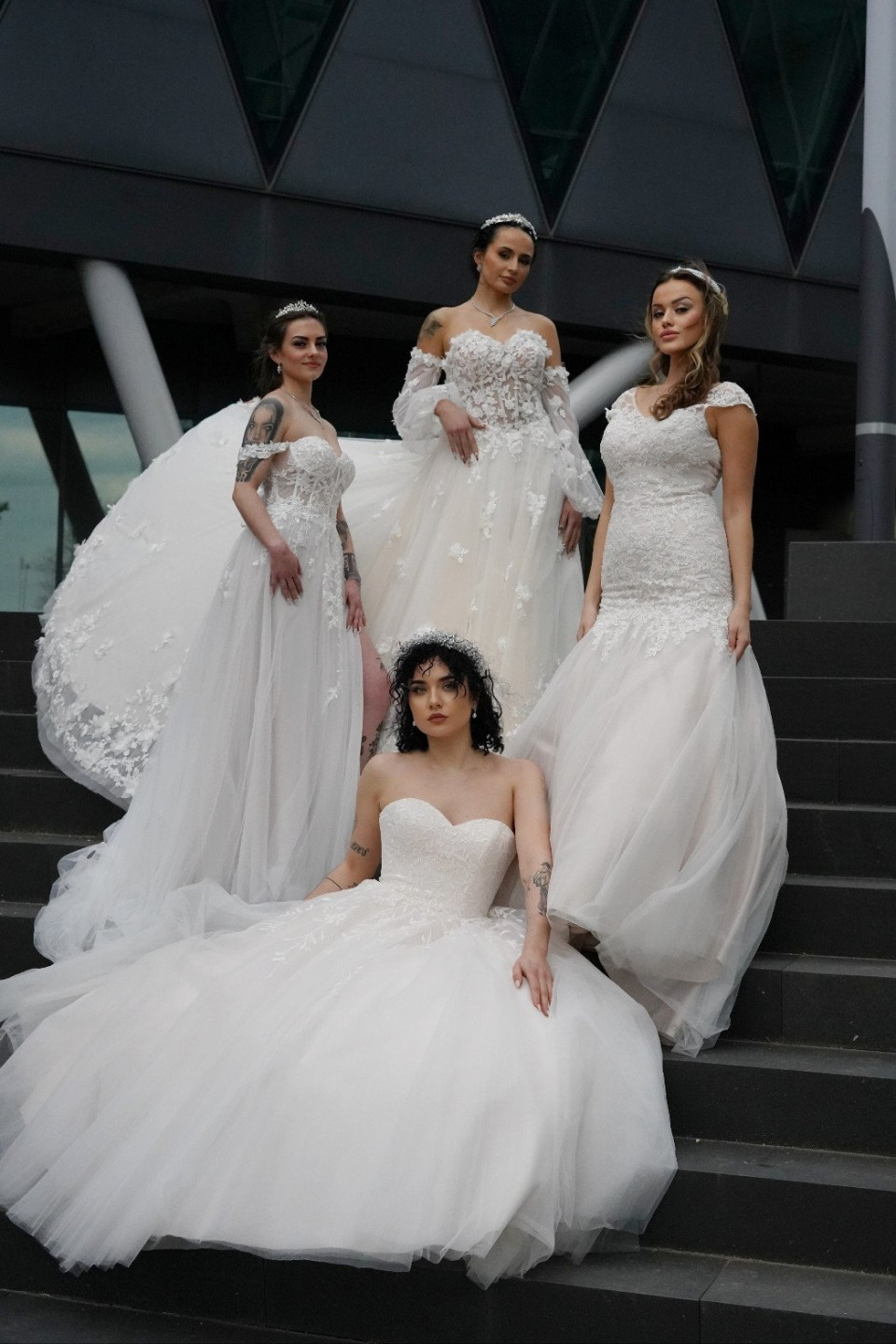 vier vrouwen in trouwjurken poseren op trappen