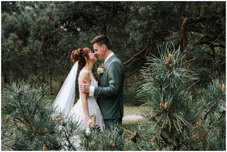 een bruid en bruidegom die in het bos kussen