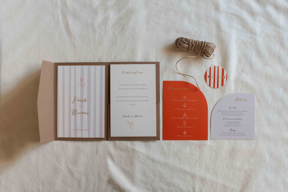 de inhoud van een trouwuitnodiging uitgespreid op een bed