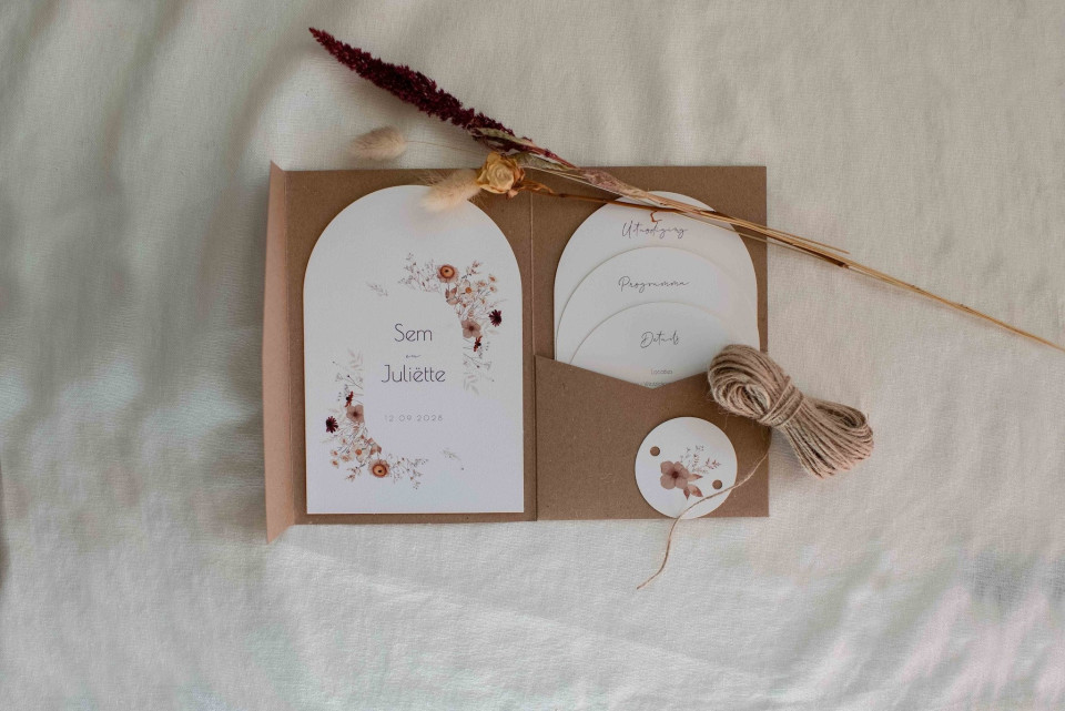 de inhoud van een trouwuitnodiging uitgestald op een bed