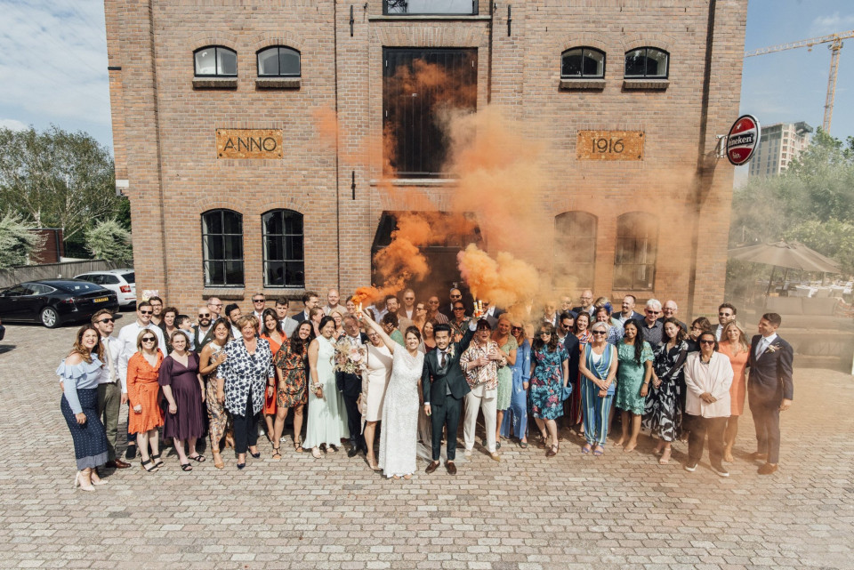 een groep mensen die voor een bakstenen gebouw met oranje rook staan