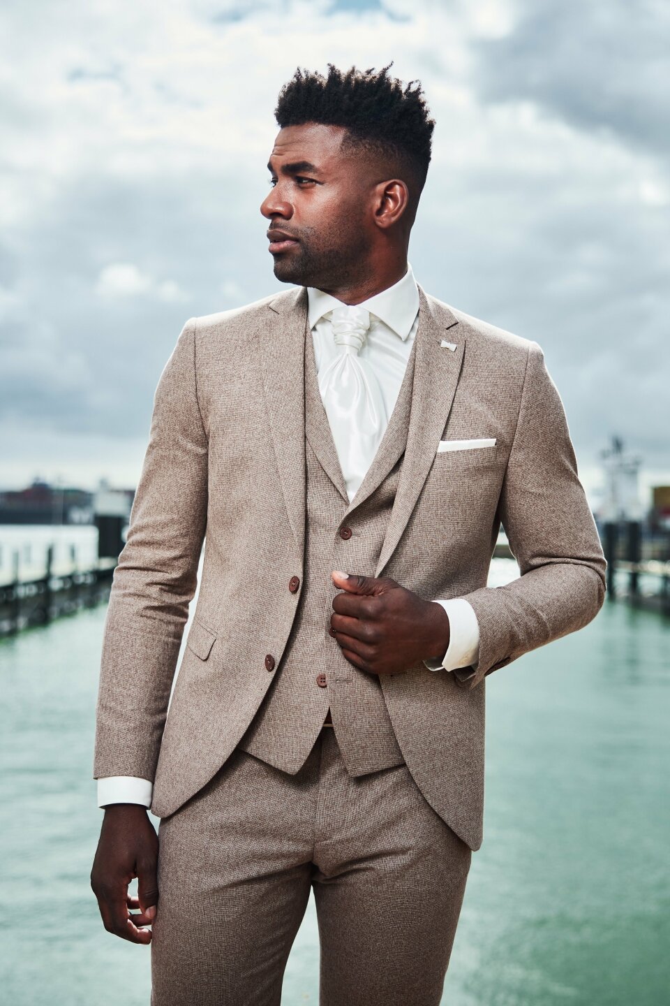 een man in een pak staand voor een waterpartij