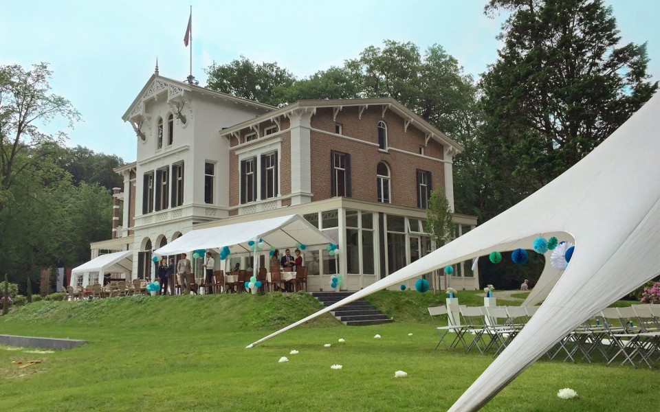 een grote witte tent met een groot huis op de achtergrond