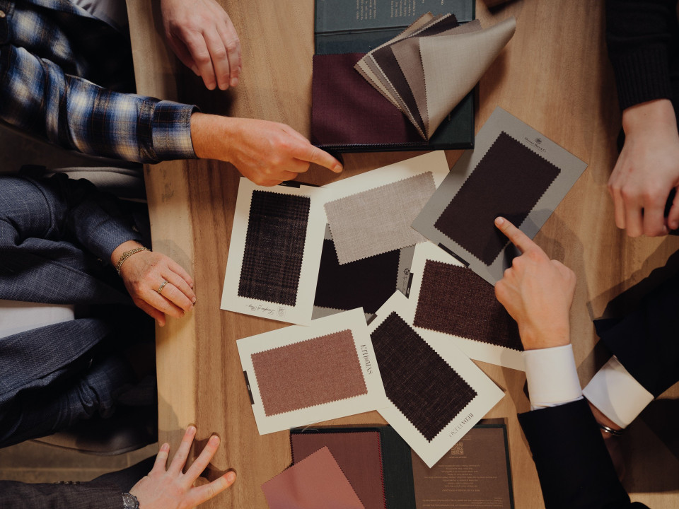 een groep mensen die rond een tafel zitten en foto's vasthouden