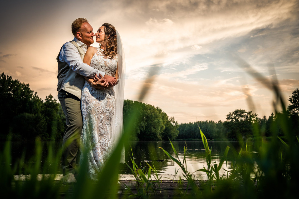 een bruid en bruidegom omhelzen elkaar voor een meer