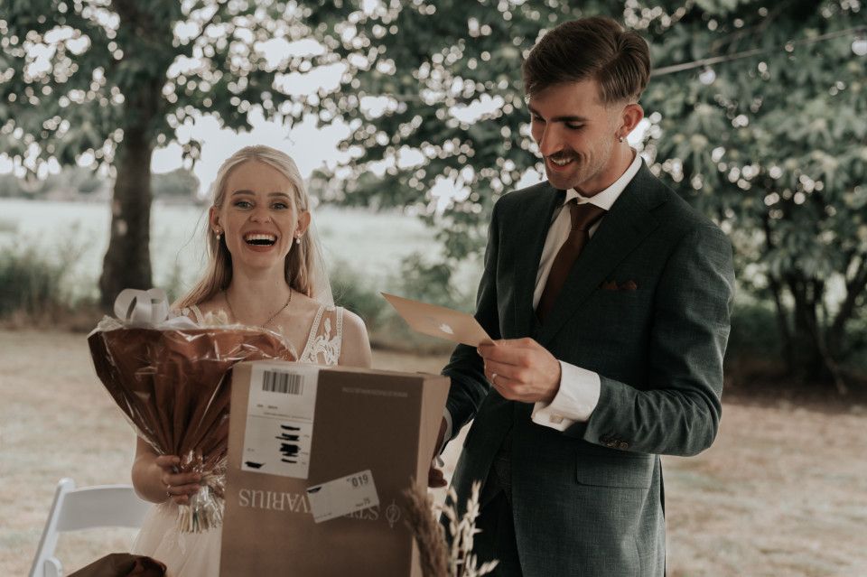 een bruid en bruidegom glimlachen terwijl ze een doos vasthouden