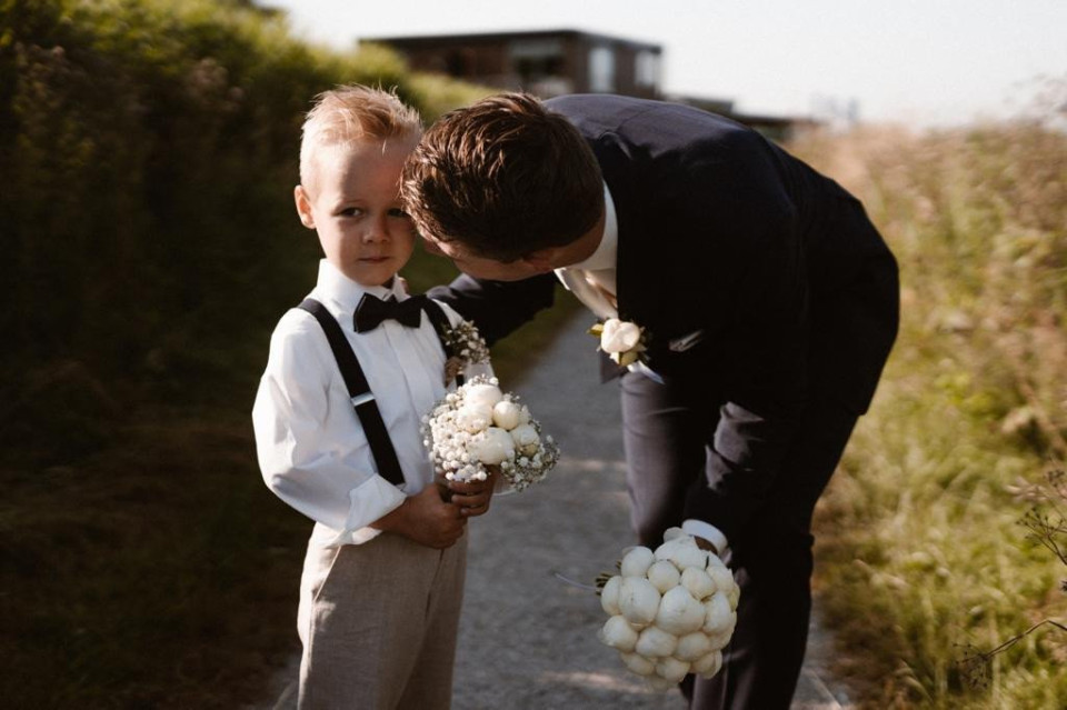 een jongen in pak en strik die een boeket vasthoudt