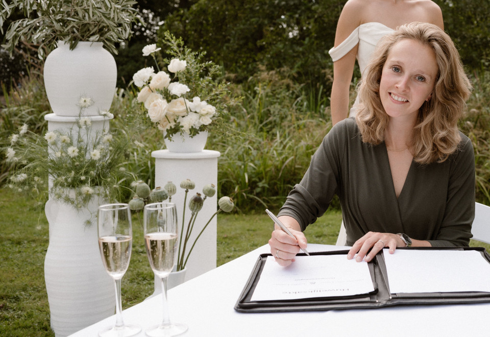 een vrouw die aan een tafel zit met een pen en papier voor zich